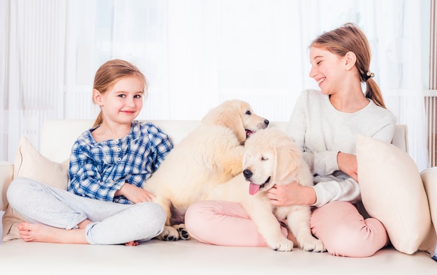 Hermanas sonrientes sentados con cachorros