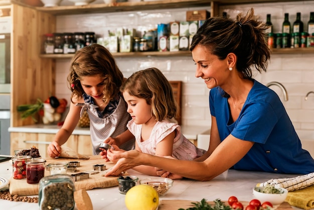 Foto hermanitas cocinando con su madre en la cocina. concepto de chef infantil.