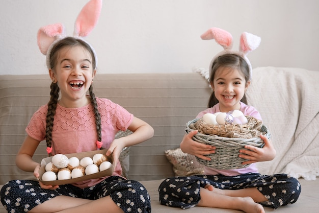 Hermanitas felices con orejas de conejo, con huevos de Pascua. Concepto de vacaciones de semana Santa.