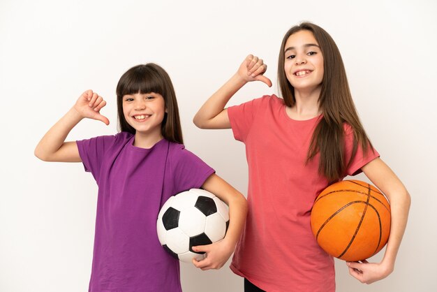 Hermanitas jugando al fútbol y baloncesto aislado sobre fondo blanco orgulloso y satisfecho de sí mismo en el concepto de amor a sí mismo