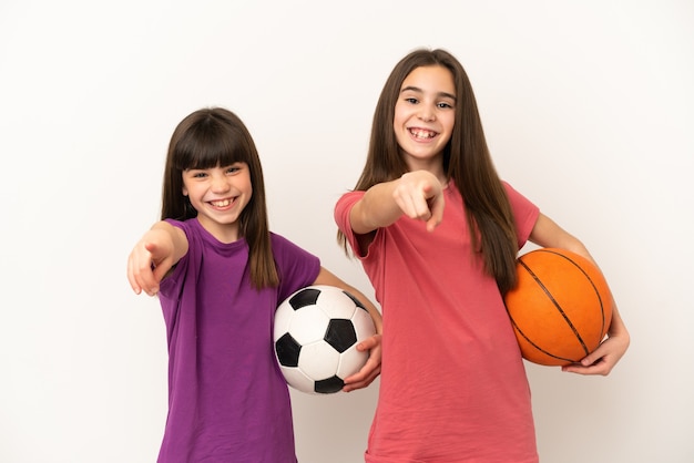 Hermanitas jugando al fútbol y baloncesto aislado sobre fondo blanco le señala con el dedo con una expresión de confianza