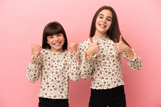 Hermanitas niñas aisladas dando un pulgar hacia arriba gesto con ambas manos y sonriendo