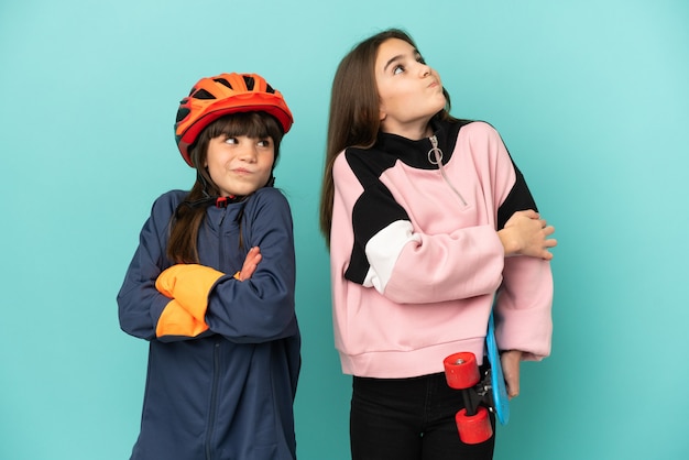 Hermanitas practicando ciclismo y patinador aislado sobre fondo azul haciendo gesto de dudas mientras levanta los hombros