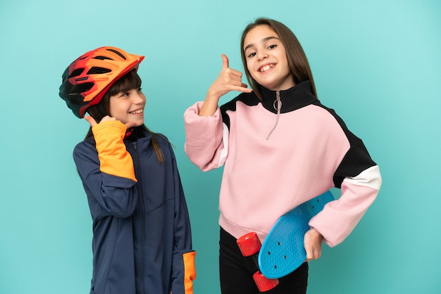 Hermanitas practicando ciclismo y patinador aislado sobre fondo azul haciendo gesto de teléfono. Llámame señal