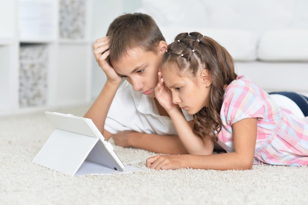 Hermano y hermana, acostado en el piso y con tableta digital