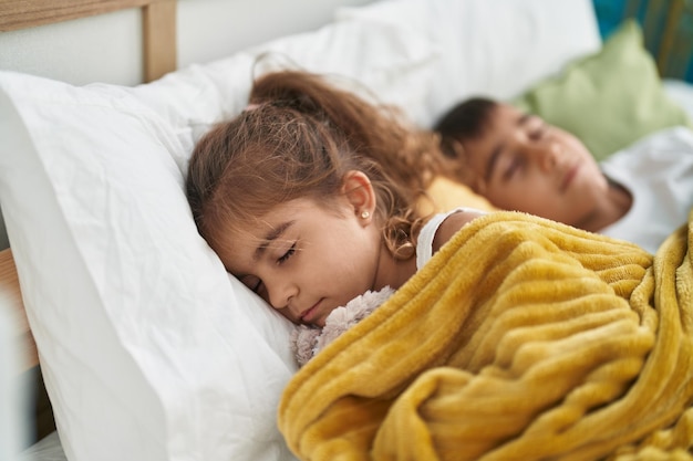 Hermano y hermana acostados en la cama durmiendo en el dormitorio