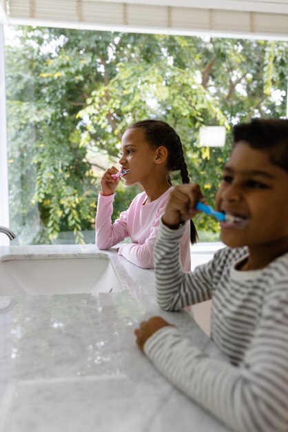 Foto hermano y hermana biraciales en pijama cepillándose los dientes juntos por la mañana en el baño. niñez, familia, cuidado personal, higiene, vida saludable y vida doméstica, inalterados.