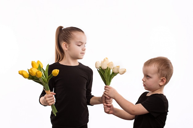 Hermano y hermana en blusas negras sosteniendo tulipanes en sus manos.