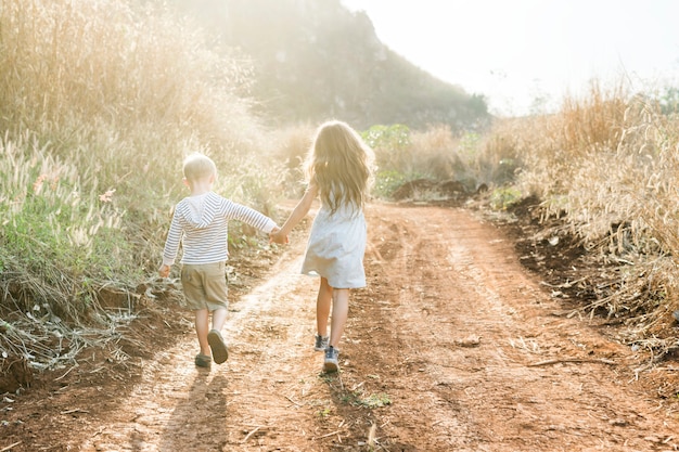 Hermano y hermana corriendo juntos en una granja