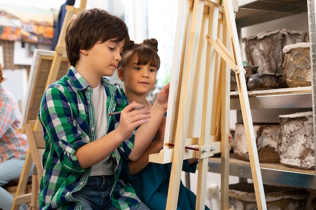 Hermano y hermana dibujando juntos en la escuela de arte