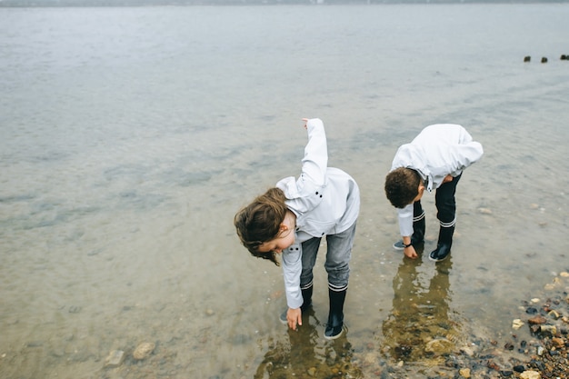 Hermano con hermana diviértete en el mar vistiendo impermeable.