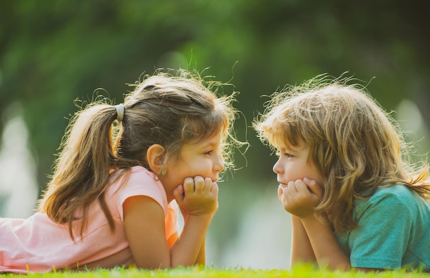 Hermano y hermana divirtiéndose en el parque dos niños alegres tumbados en la hierba verde familia feliz...