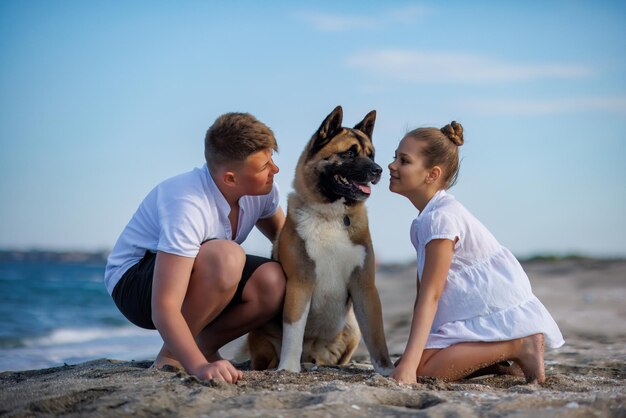 Hermano y hermana están caminando y con un perro de raza Akita Inu a lo largo de la costa del Mar Negro