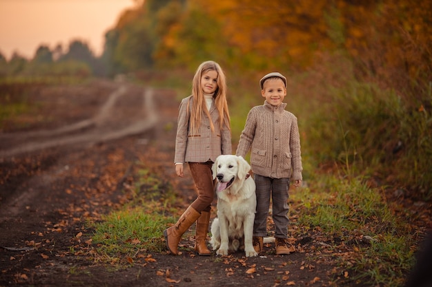 Hermano y hermana de hermosos niños felices están paseando a su perro perdiguero