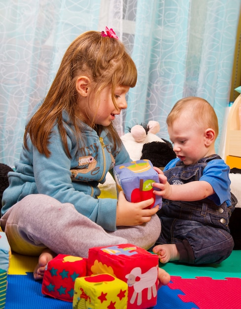 Hermano y hermana jugando con cubo de colores suaves