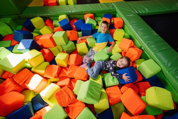 Hermano con hermana jugando en el patio interior del centro de juegos en la piscina de cubos de color