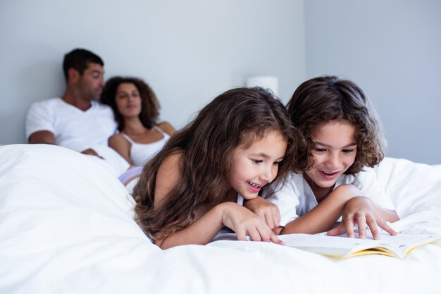 Hermano y hermana leyendo un libro juntos en la cama