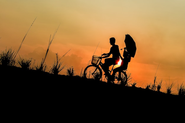 hermano con hermana montando bicicletas al atardecer