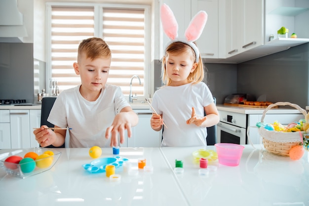 Hermano y hermana pintando huevos de Pascua.