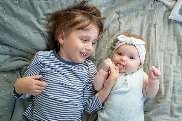 Hermano hermano acostado en la cama con su hermana pequeña Niño preescolar sosteniendo la mano del bebé con ternura y cuidado Nuevo miembro de la familia gran familia