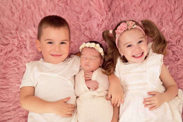 Foto hermano mayor y hermana con hermanita recién nacida