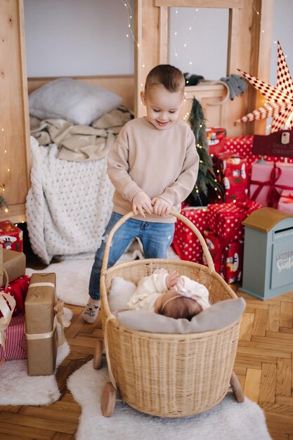 El hermano pequeño juega con su pequeño siter. Los niños lindos juegan durante las vacaciones de invierno. Estado de ánimo navideño.