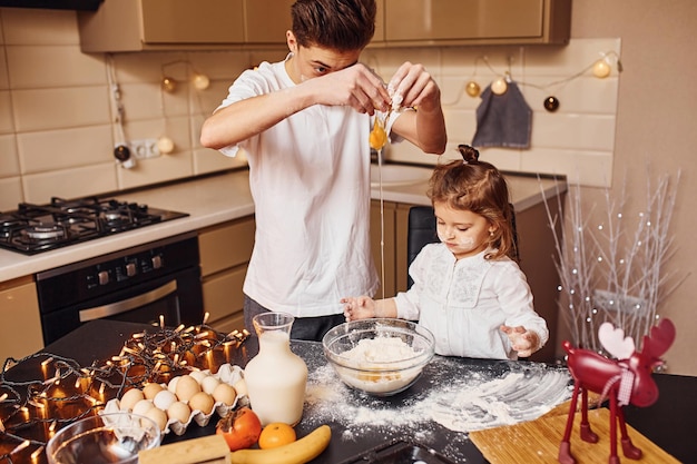 Hermano con su hermana pequeña preparando comida en la cocina y diviértete.