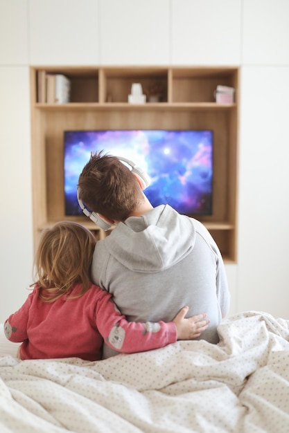 Hermano y su hermana pequeña viendo televisión niños jugando videojuegos en casa