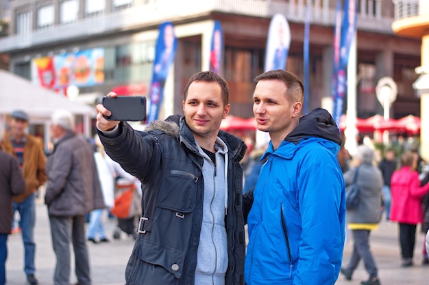 Foto hermano tomando una selfie mientras está de pie en la calle en la ciudad
