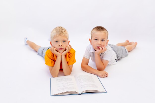 Hermanos acostado sobre un fondo blanco aislado y leyendo un libro