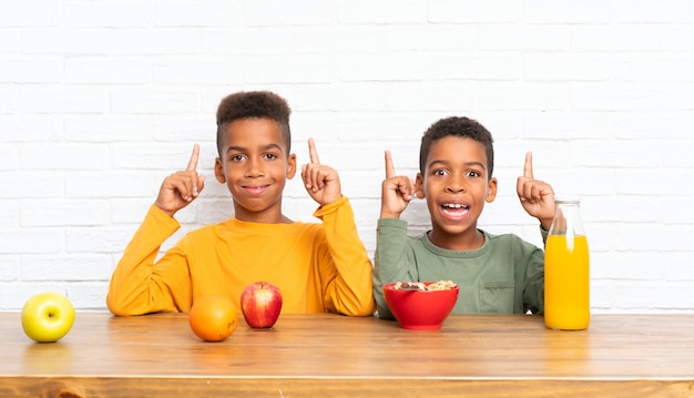 Hermanos afroamericanos desayunando y apuntando hacia arriba