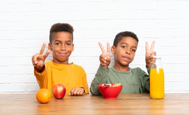 Hermanos afroamericanos desayunando y haciendo gesto de victoria