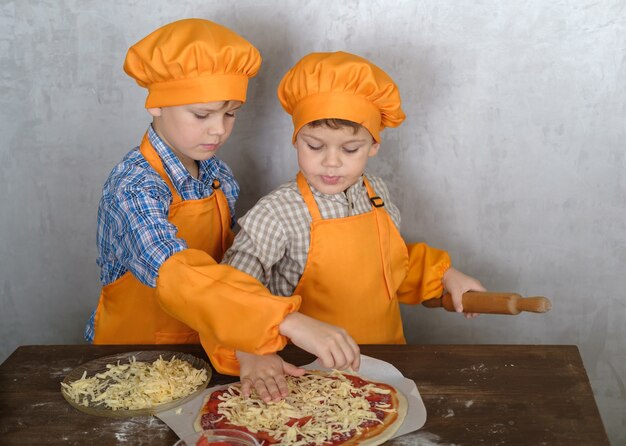 hermanos ayudan a mamá a cocinar pizza con salchicha y queso