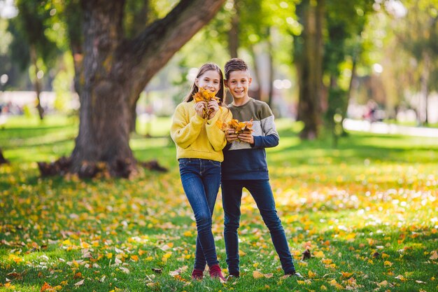 Foto hermanos caucásicos felices disfrutando en día de otoño en el parque