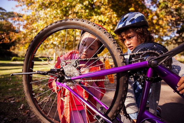 Hermanos concentrados reparando bicicleta de montaña