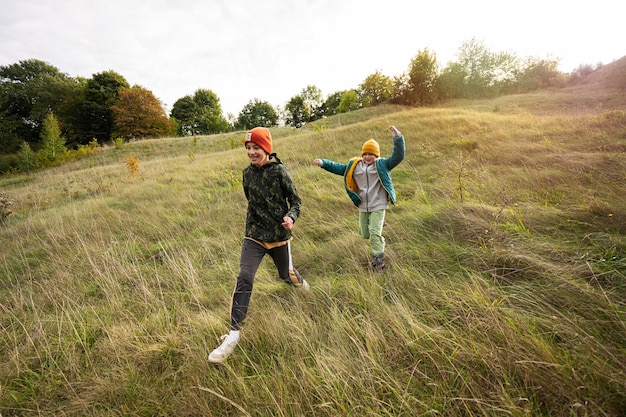 Hermanos divirtiéndose correr y saltar al aire libre cerca del bosque