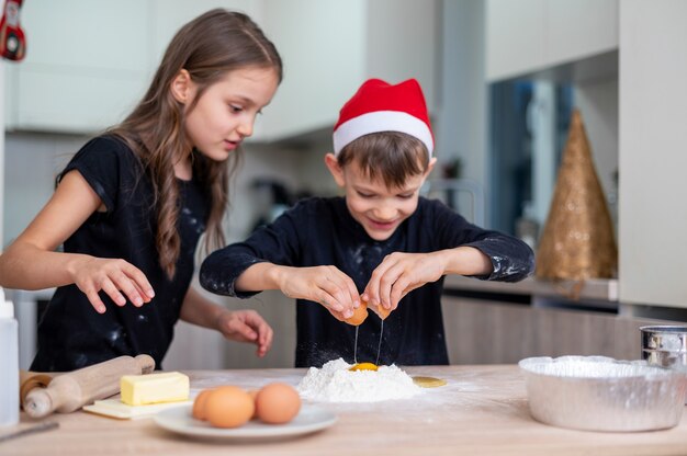 Los hermanos están cocinando en la cocina, niño con sombrero de Navidad. Idea de niños felices