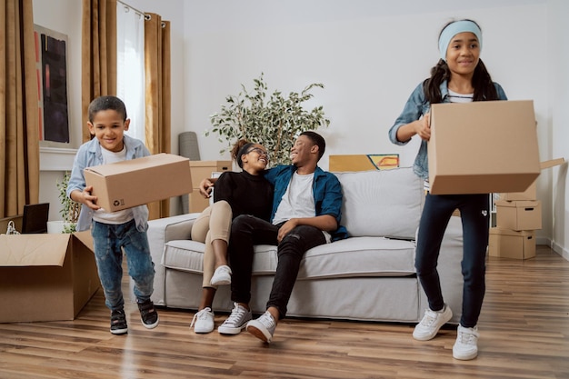 Los hermanos están limpiando la sala de estar de las cajas que quedaron después de la mudanza. La niña y el niño se están mudando.