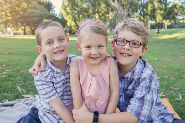 Hermanos felices y hermana jugando en el parque