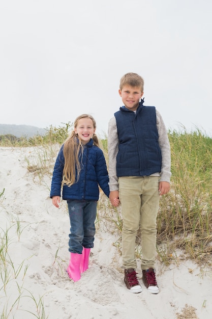 Hermanos felices que se colocan de común acuerdo en la playa