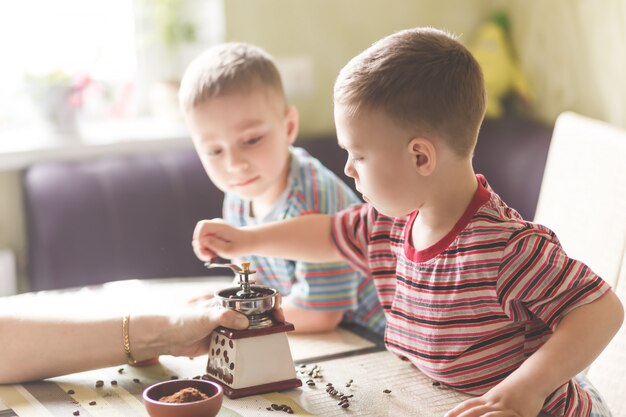 Foto hermanos gemelos ayudando a su madre a moler café