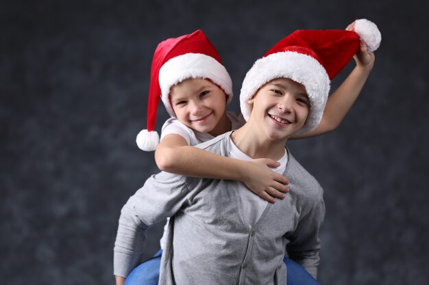 Hermanos con gorros de Papá Noel se divierten