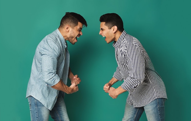 Hermanos gritando, gritándose el uno al otro, de pie frente a frente en el fondo del estudio