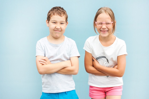 Hermanos y hermanas niños gemelos de 8 años de edad con caras divertidas sobre fondo azul