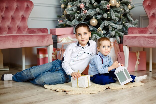 Hermanos jóvenes cerca del árbol de Navidad