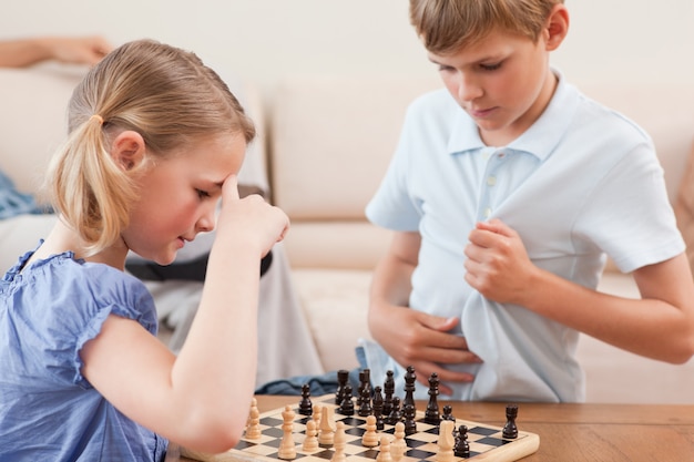 Foto hermanos jugando al ajedrez en una sala de estar