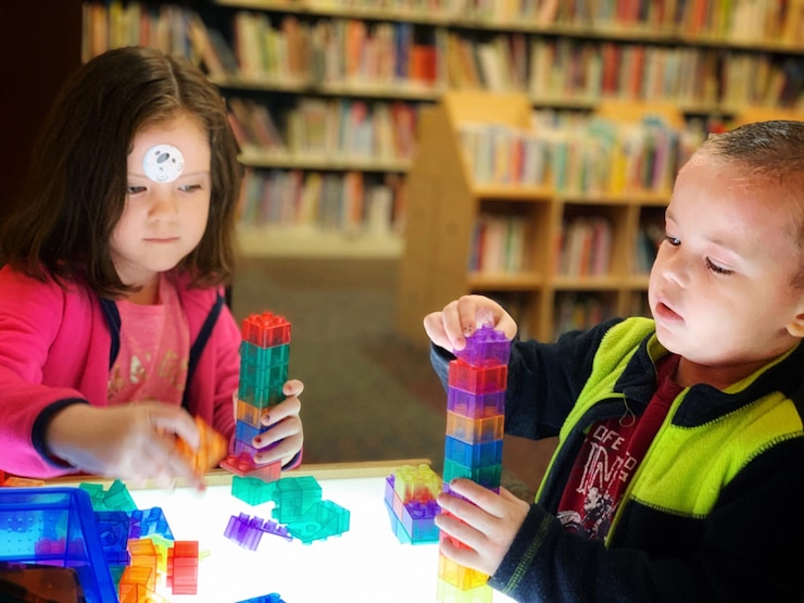 Foto hermanos jugando con bloques de juguete en la mesa de la biblioteca