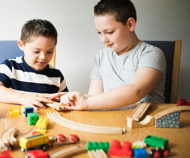 Hermanos jugando con bloques, trenes y coches.