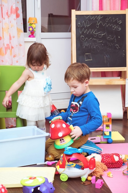 Foto hermanos jugando con juguetes en casa