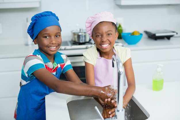 Hermanos lavarse las manos en la cocina en casa